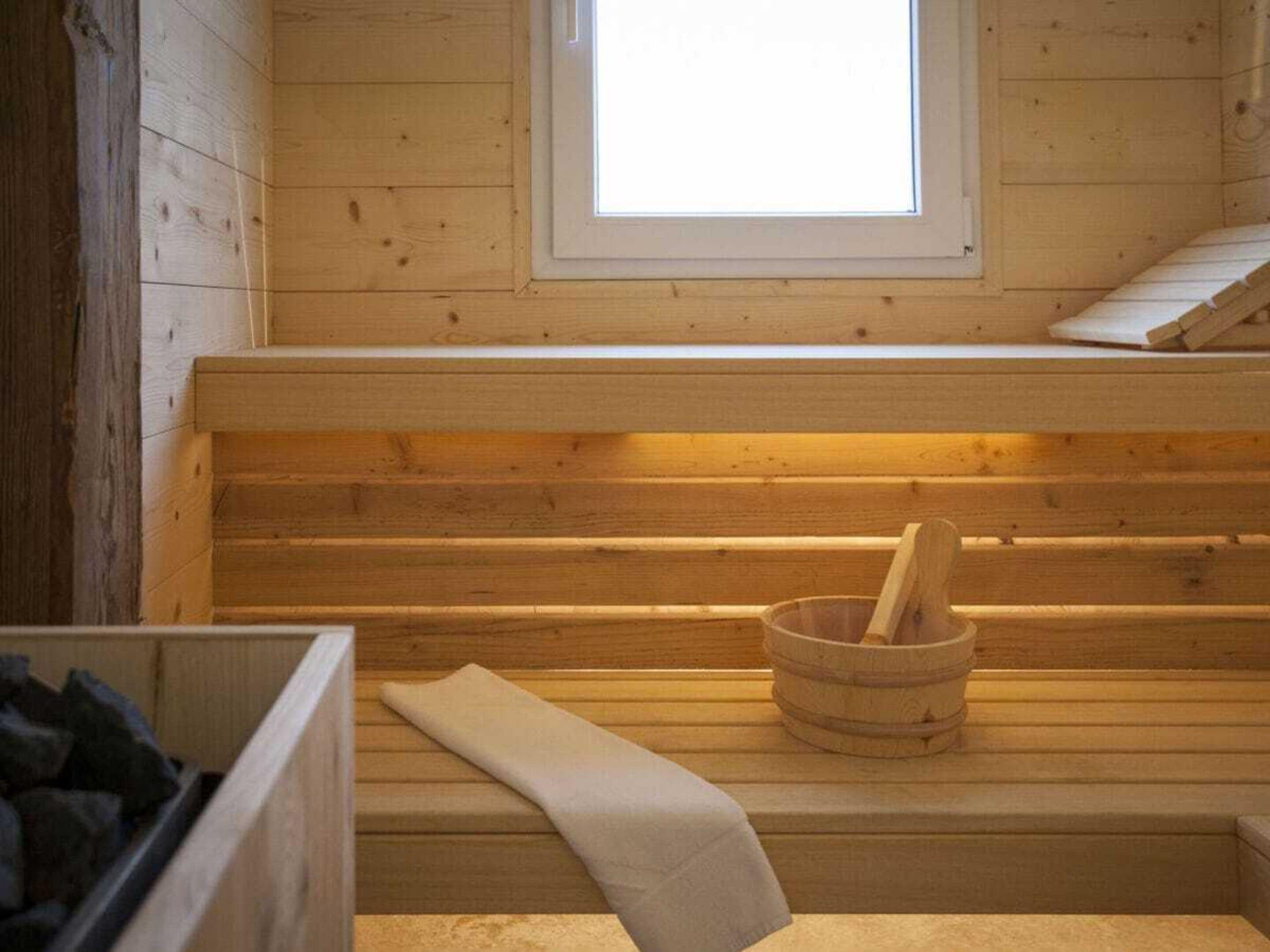 A wooden cabin interior with a bench, a window, and a fireplace.