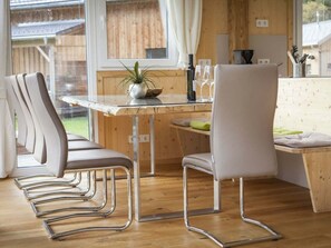 A modern kitchen with a wooden table and chairs, a potted plant, and a view of the outdoors. - Cabin in Murau With Sauna and Terrace (Murau)