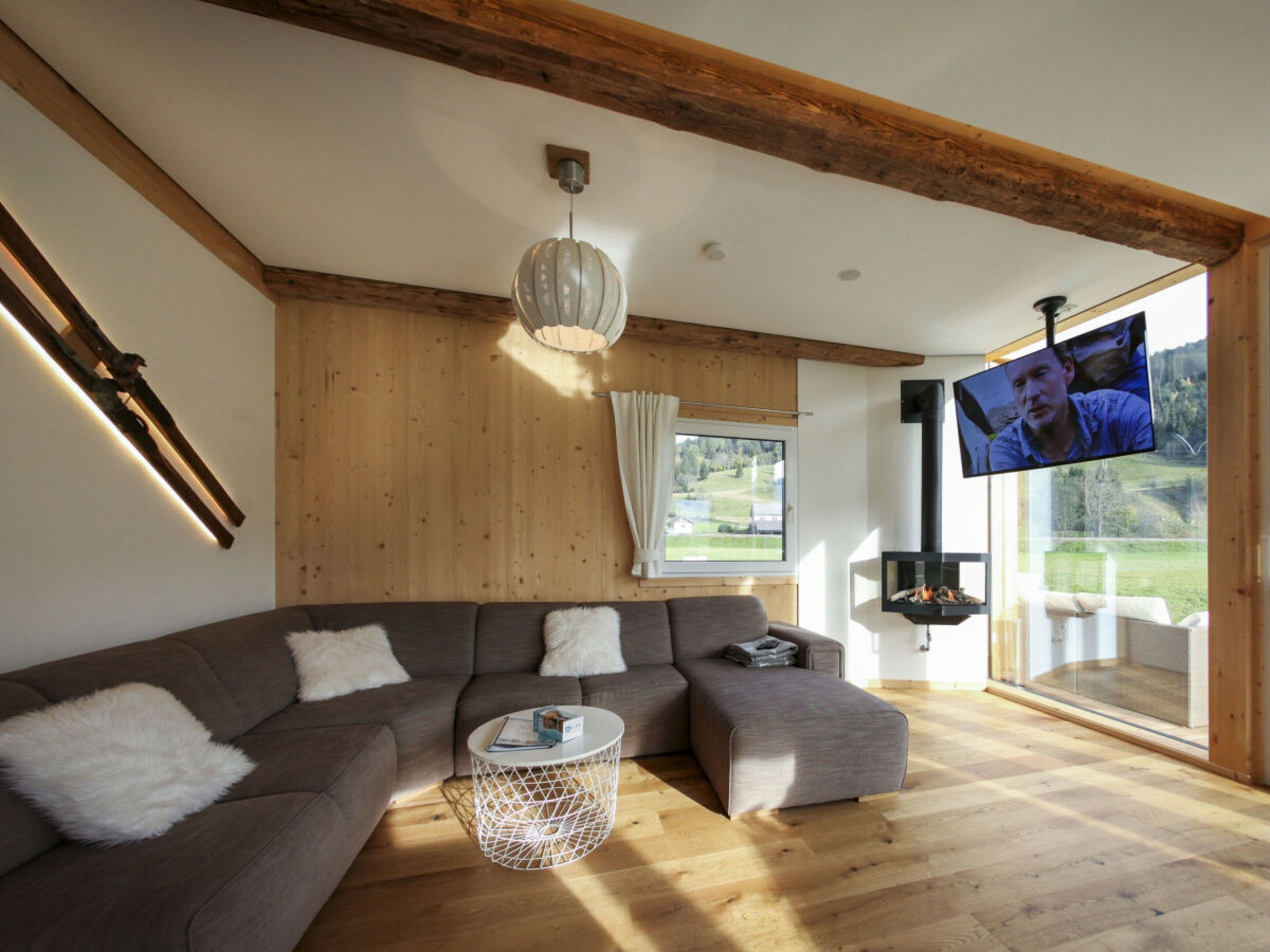 A modern living room with a sectional sofa, a round coffee table, and a television mounted on the wall.