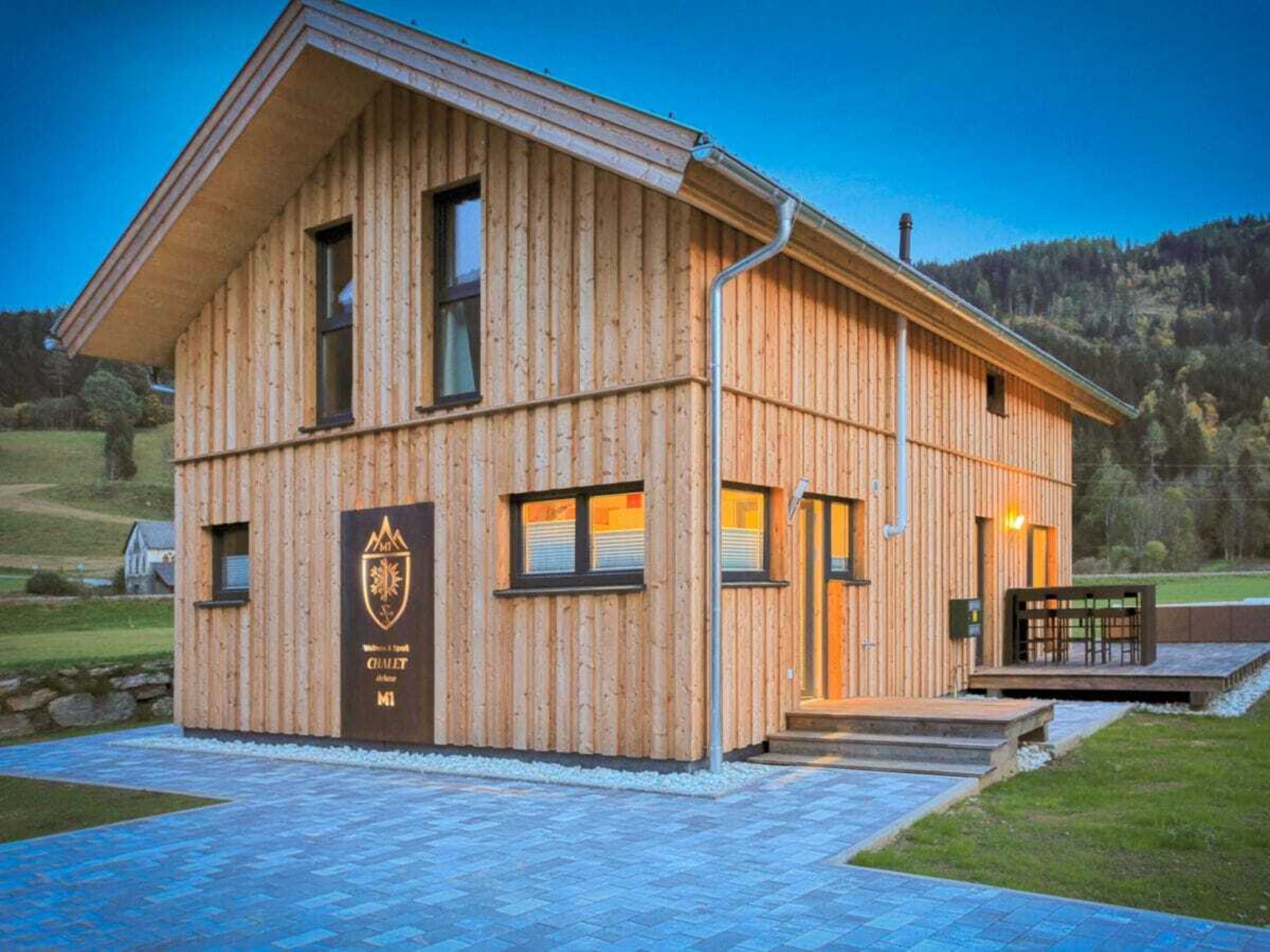 A wooden building with a sloped roof, a front entrance, and a logo on the side.