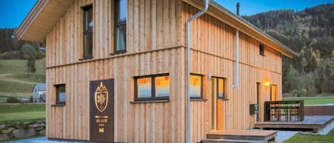 A wooden building with a sloped roof, a front entrance, and a logo on the side.