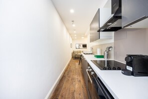 A modern kitchen with a white countertop, stainless steel appliances, and a wooden floor. - Earl`s Court Residence | Elegant 1BR | London (London)
