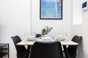 A dining area with a table set for four, chairs, a vase with flowers, and a framed picture on the wall. - Earl`s Court Residence | Elegant 1BR | London (London)