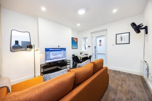 A modern living room with a sofa, a dining table, and a TV. - Earl`s Court Residence | Elegant 1BR | London (London)