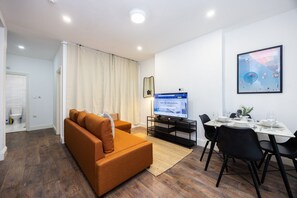 A modern living room with a sofa, a dining table set for two, and a television. - Earl`s Court Residence | Elegant 1BR | London (London)