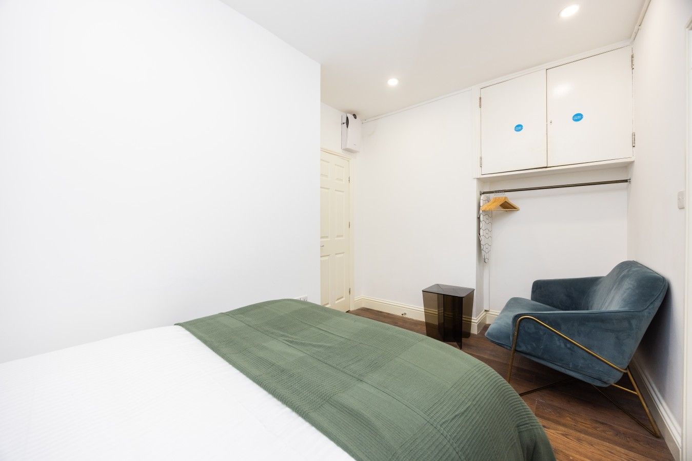 Quarto com cama, cadeira, guarda-roupa e uma pequena mesa.