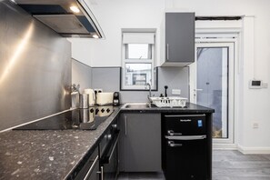 Une cuisine moderne équipée d’une cuisinière intégrée, d’un lave-vaisselle et d’une fenêtre située au-dessus de l’évier.