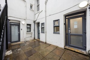 A narrow alleyway with a tiled floor, a door with a number plate, and a window with a curtain. - Earl`s Court Residence | Elegant Studio | London (Greater London)