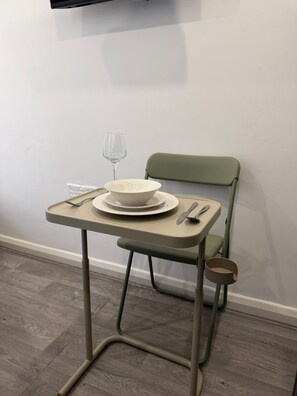 A small dining table with a bowl, plates, cutlery, and a wine glass. - Earl`s Court Residence | Elegant Studio | London (Greater London)