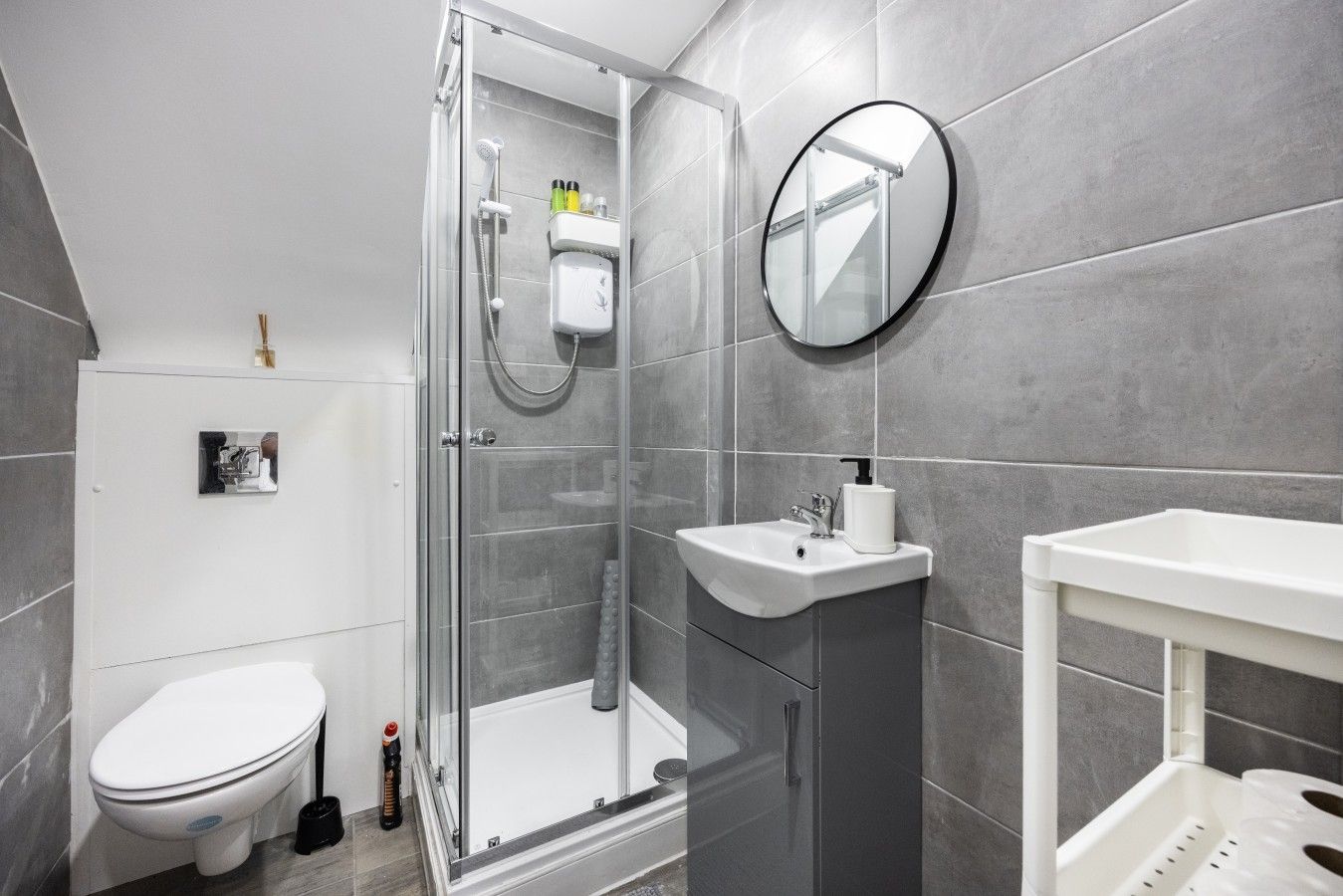 Uma casa de banho moderna com chuveiro em cabine de vidro, lavatório branco e sanita.