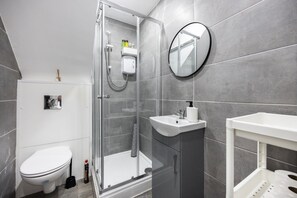 Une salle de bain moderne avec une douche à parois de verre, un lavabo blanc et des toilettes.
