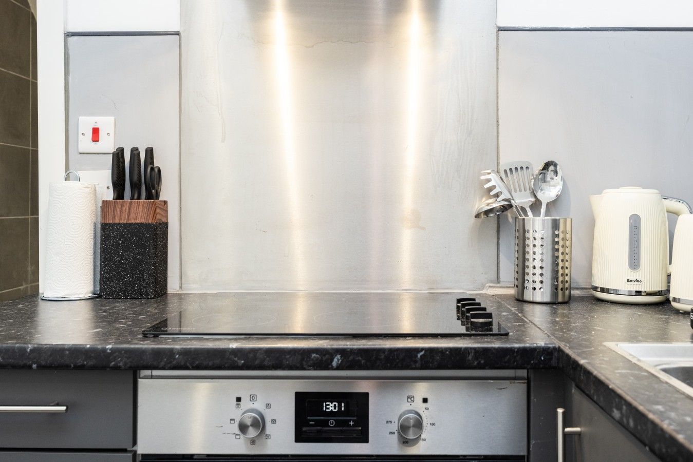 A kitchen with a stainless steel range hood, a digital clock, and a coffee maker.