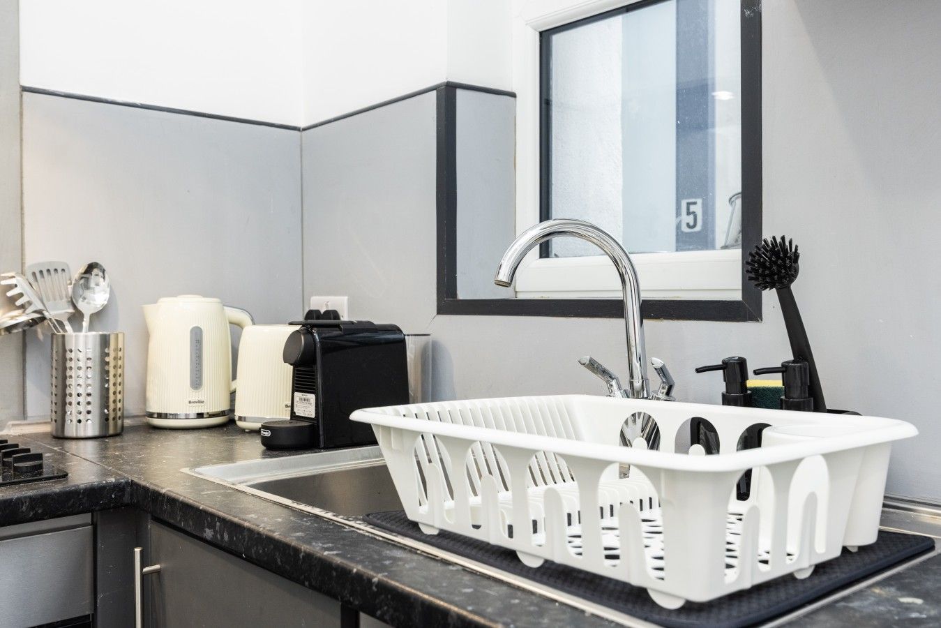 Une cuisine moderne avec un évier blanc, des appareils en acier inoxydable et une fenêtre offrant une belle vue.