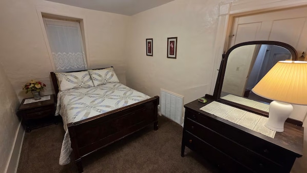 A bedroom with a bed, a dresser, a mirror, and a radiator.