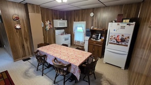 A compact kitchen with a dining table, chairs, a microwave, a stove, and a refrigerator.