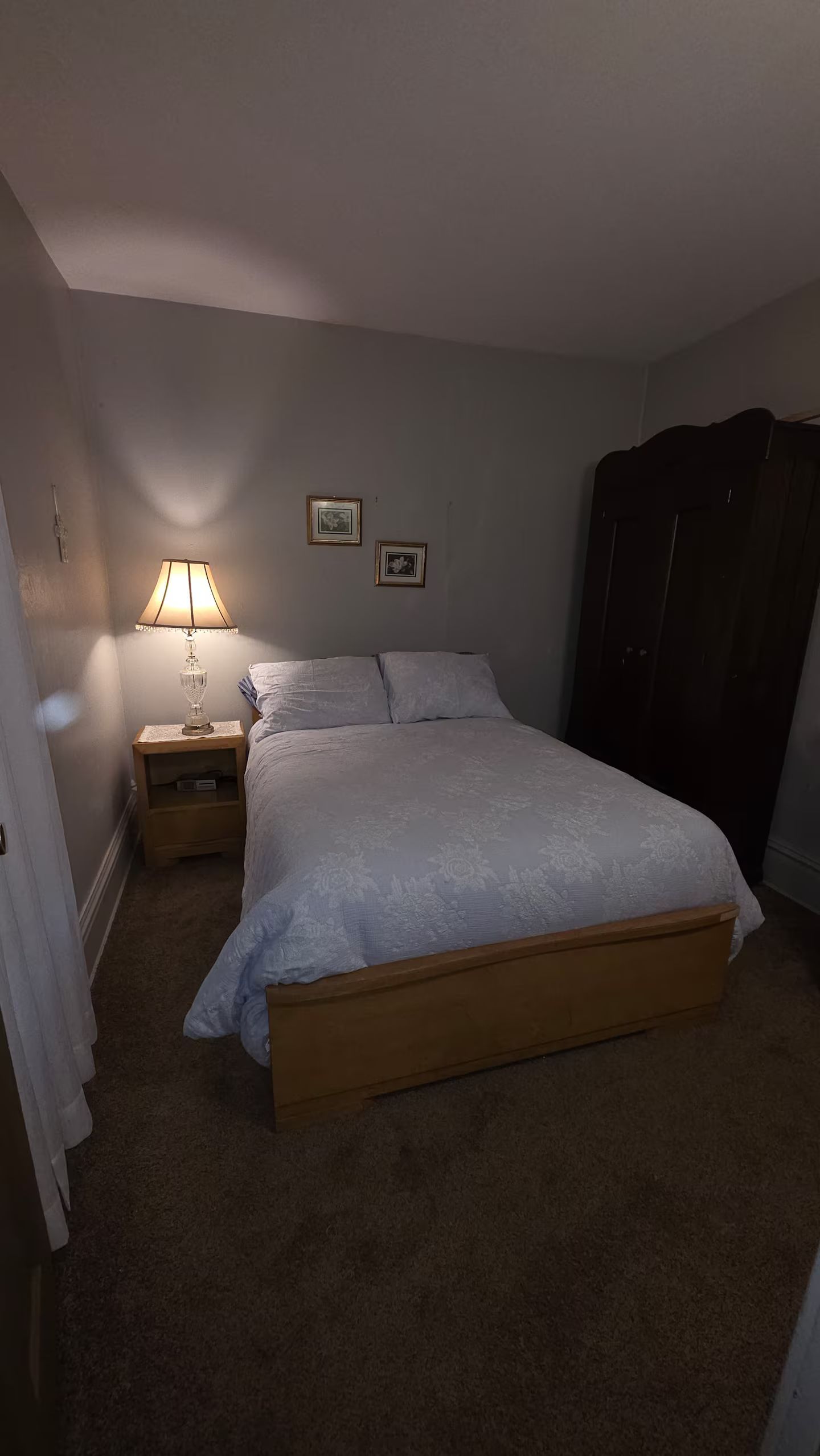 Un dormitorio con cama, mesita de noche, lámpara y armario.