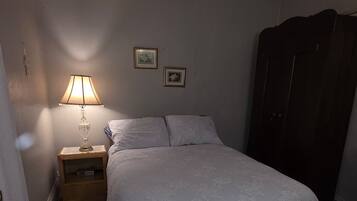 Une chambre à coucher avec un lit, une table de chevet, une lampe et une armoire.