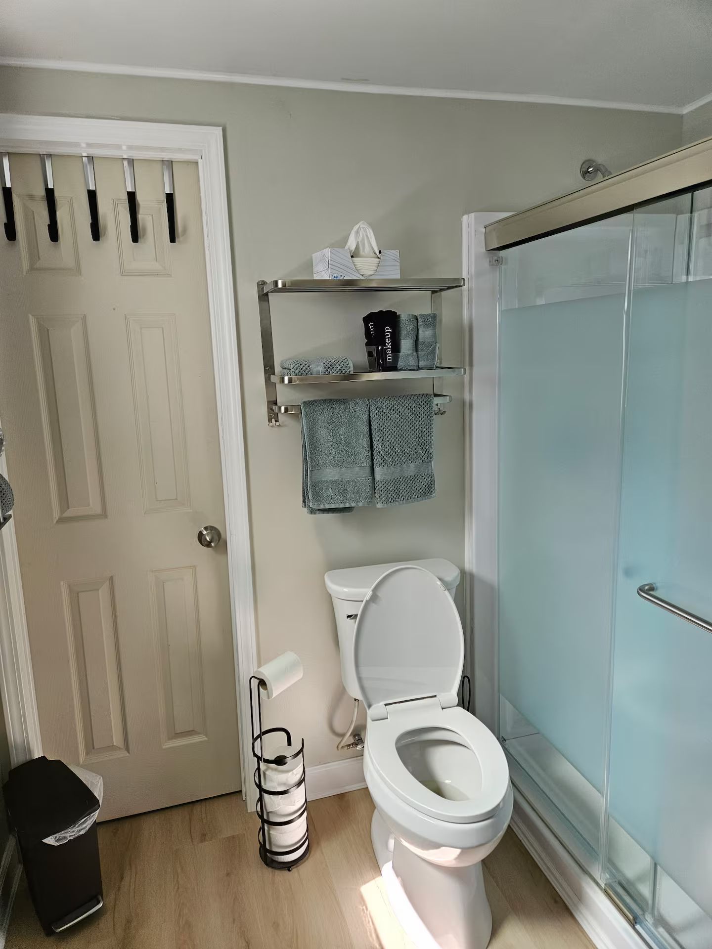 Une salle de bain comprenant des toilettes, un espace de douche vitré, un porte-serviettes avec des serviettes et une poubelle.