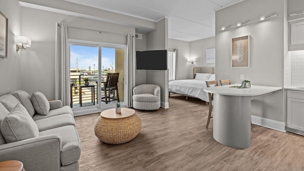 Habitación de hotel moderna con sofá, una mesa redonda, cama, televisión y balcón con vistas.