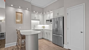 Una cocina moderna con armarios blancos, un refrigerador de acero inoxidable y una isla central.
