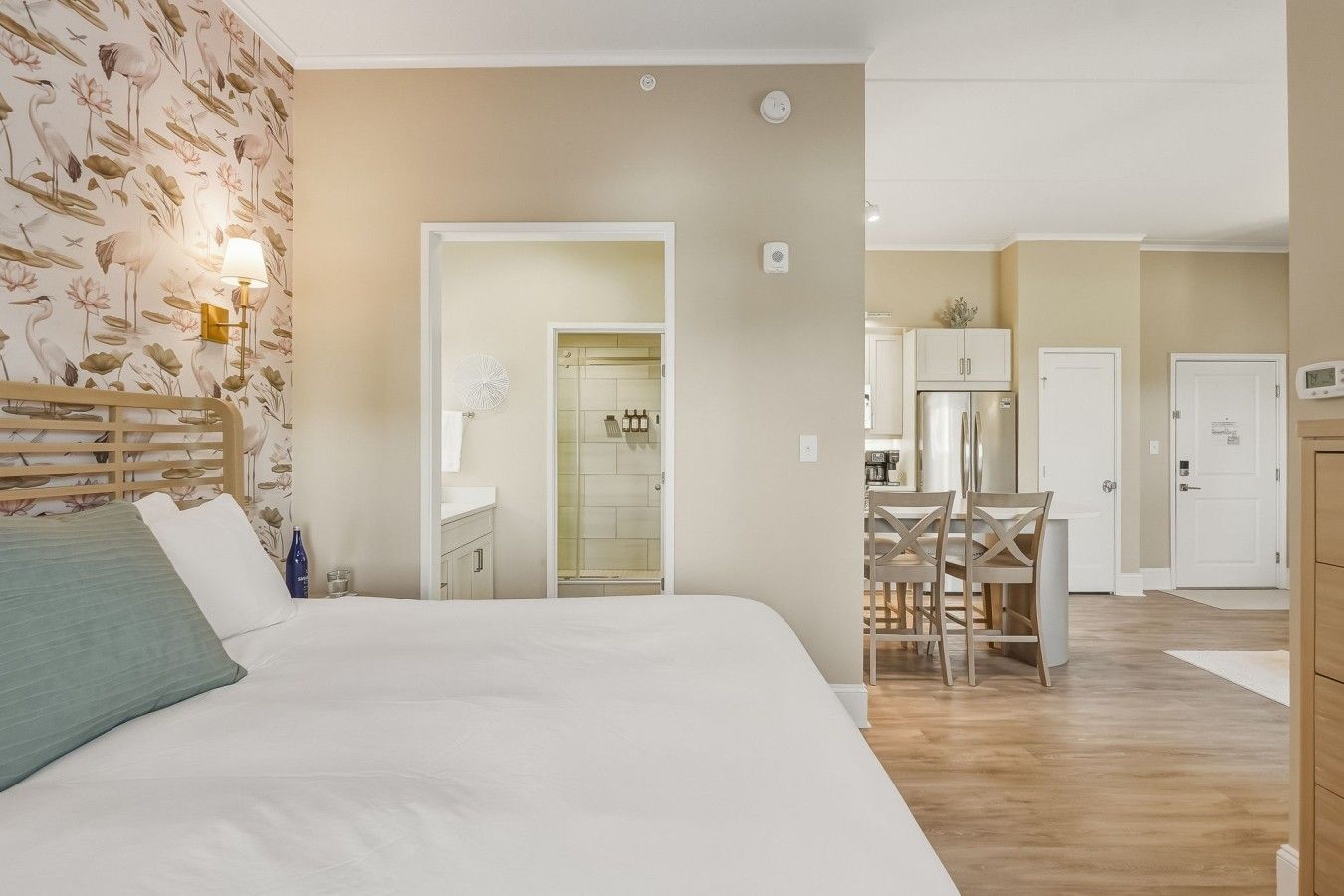 Une chambre d’hôtel comprenant un lit, une salle de bain avec douche, un coin repas avec une table et des chaises, et un coin cuisine.