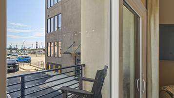Een balkon met uitzicht op een parkeerplaats en een gebouw met grote ramen.