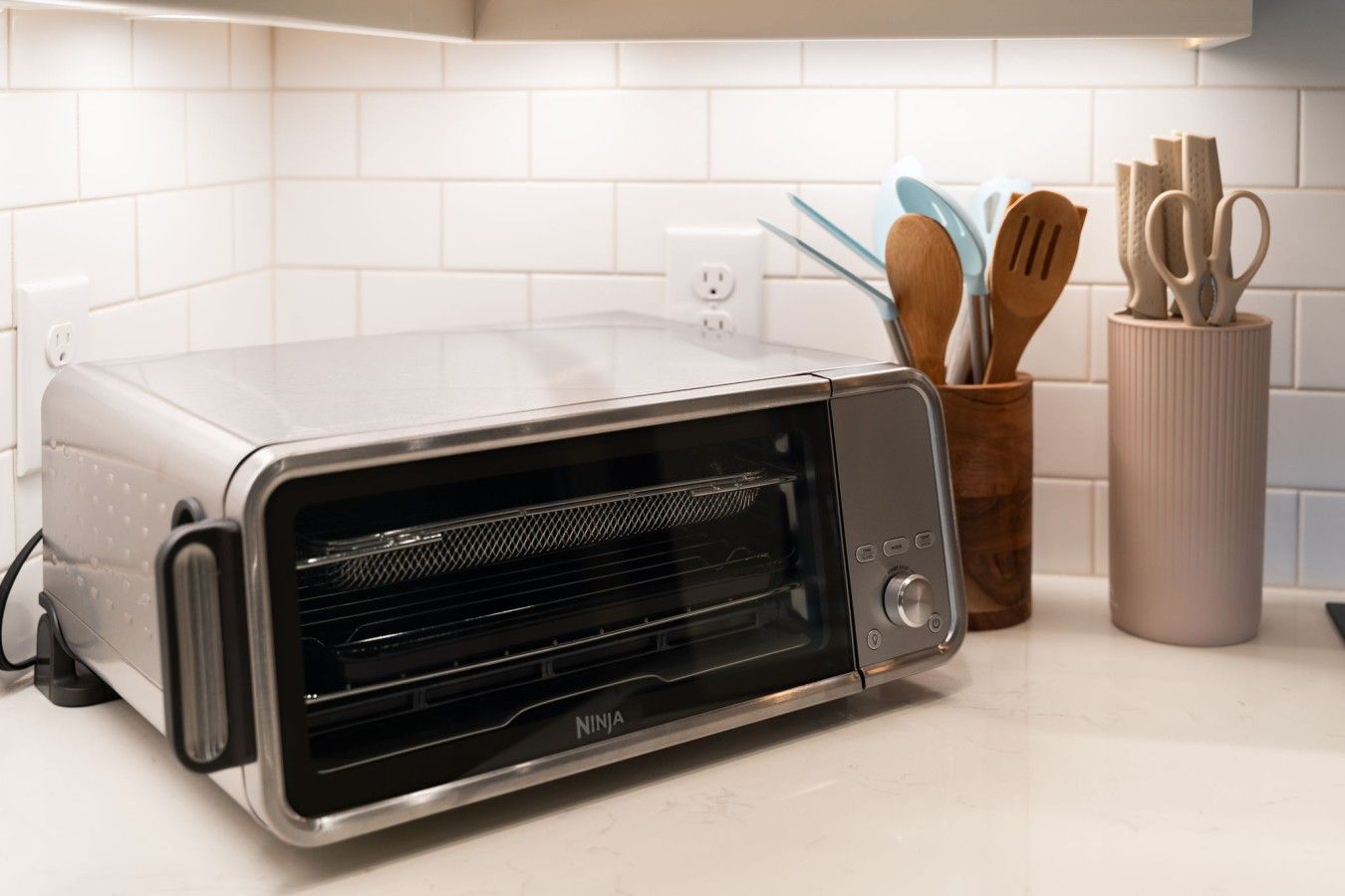 Eine Küche mit einem Toaster auf der Arbeitsplatte, einem Messerblock und einem Löffelhalter.