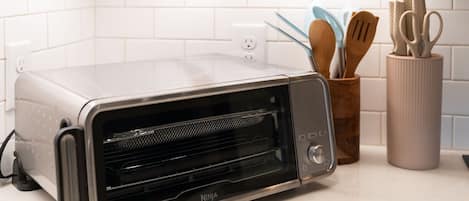 Uma cozinha com forno elétrico na bancada, porta-facas e suporte para colheres.