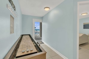 Ein Zimmer mit einem Shuffleboardtisch, einer Tür zu einem Balkon und einem Bett.