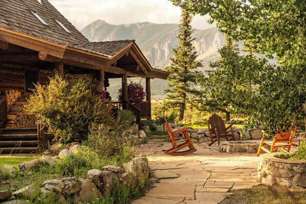 Un rustico chalet con un portico, immerso nel verde e un sentiero in pietra.