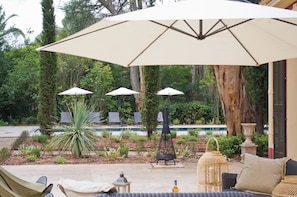 A patio area with outdoor seating, umbrellas, and a pool. - Villa Médicis – Sleeps 10, Private Pool, A/C & Walking Distance to the Sea (Le Pradet)