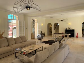 A spacious living room with a sofa, coffee table, and a piano. - Villa Médicis – Sleeps 10, Private Pool, A/C & Walking Distance to the Sea (Le Pradet)