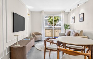 Ein modernes Wohnzimmer mit Fernseher, einem runden Esstisch und einer Couch.