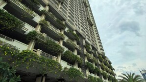 Een hoog gebouw met meerdere balkons, waarvan sommige beplant zijn.