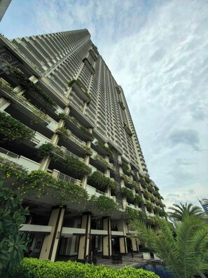 Un immeuble de grande hauteur doté de nombreux balcons, dont certains sont ornés de plantes.