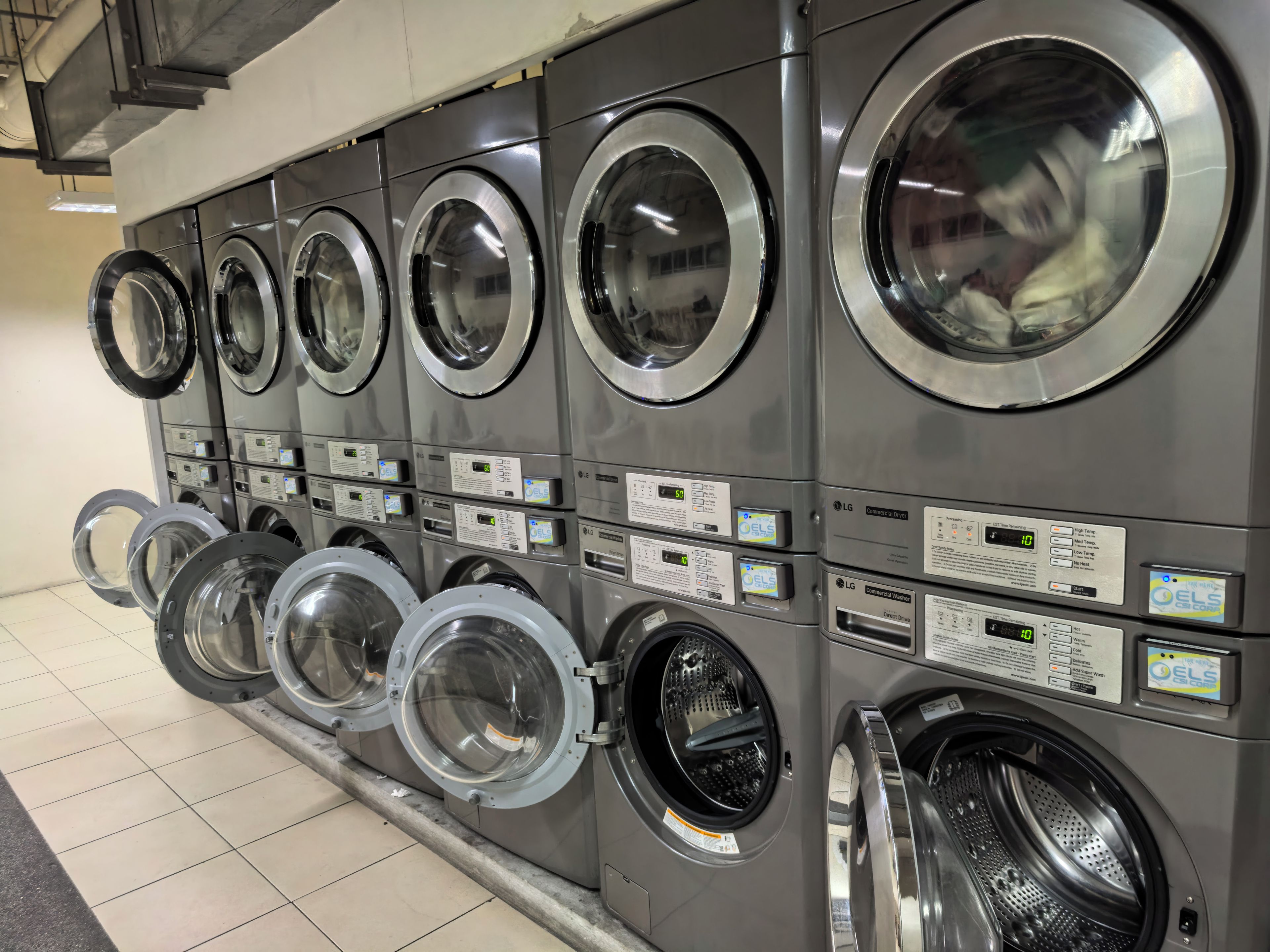 A row of commercial laundry machines with control panels and digital displays.