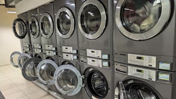 A row of commercial laundry machines with control panels and digital displays.
