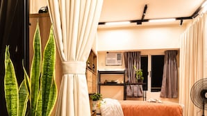 Een kleine slaapkamer met een bed, nachtkastje en een potplant.