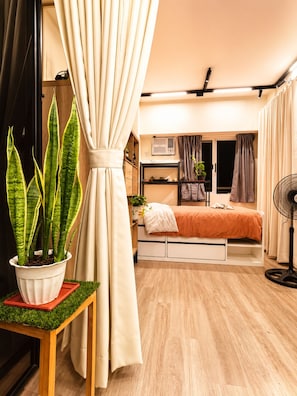 Une chambre à coucher de taille réduite, comprenant un lit, une table de chevet et une plante en pot.
