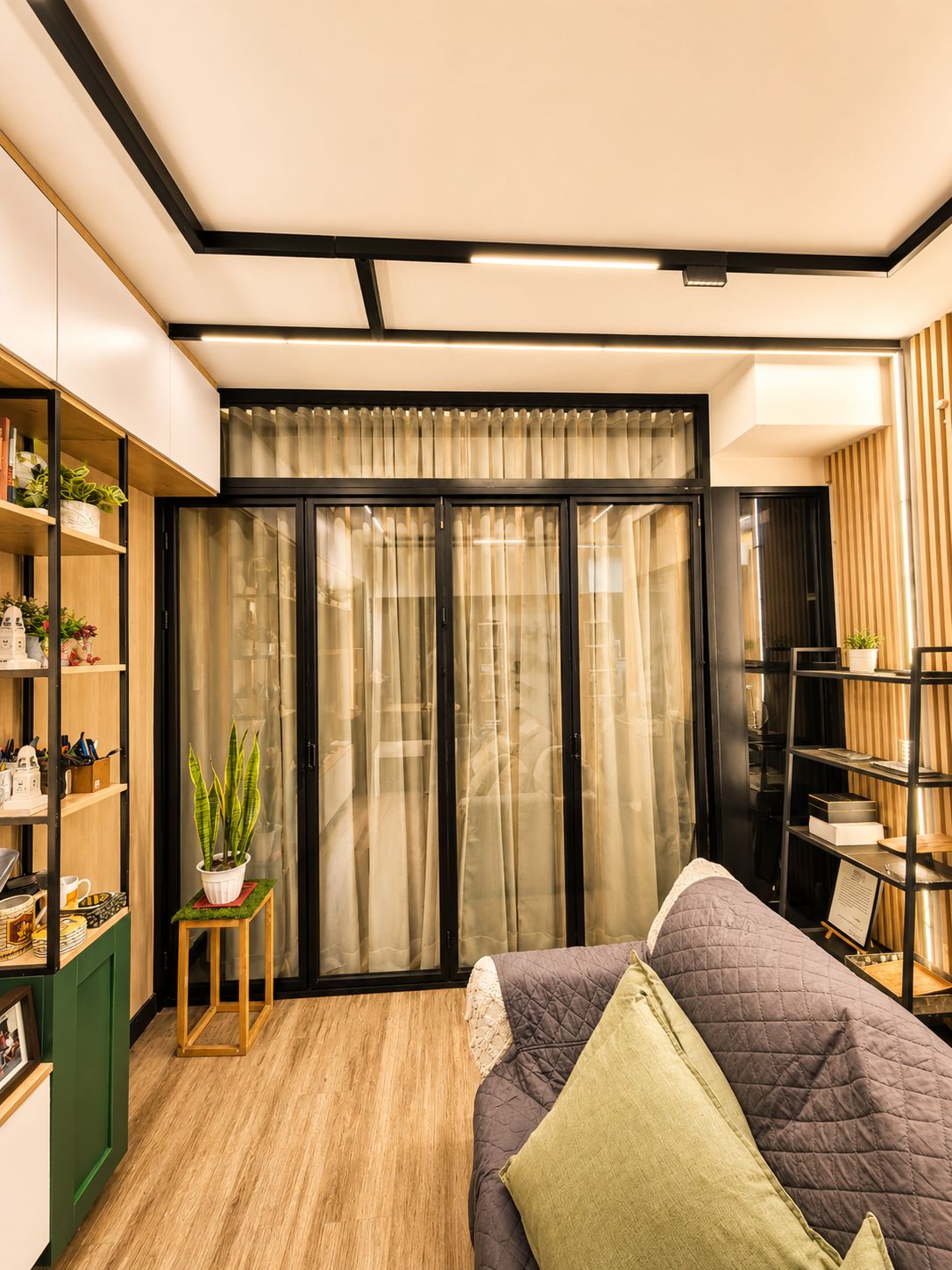 A bedroom with a bed, a bookshelf, a potted plant, and a sliding door with curtains.