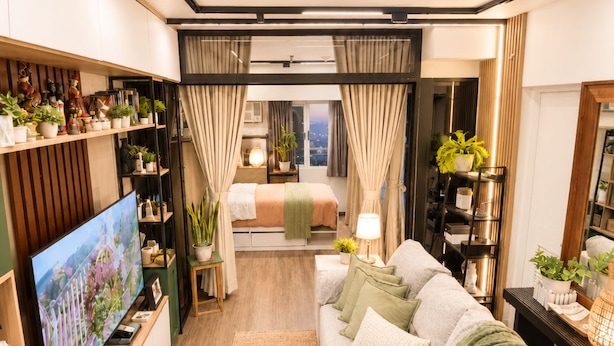 Een moderne woonkamer met een flatscreen televisie, een bank, een salontafel en een groot raam met gordijnen.