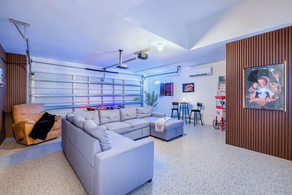 A modern living room with a sectional sofa, a flat-screen TV, and a popcorn machine.