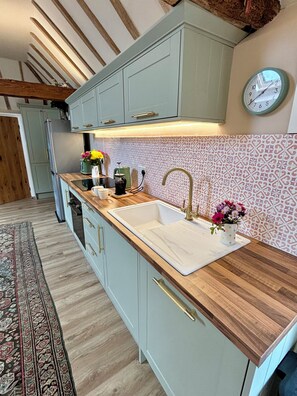 A modern kitchen with a wooden countertop, a sink, and a clock on the wall.