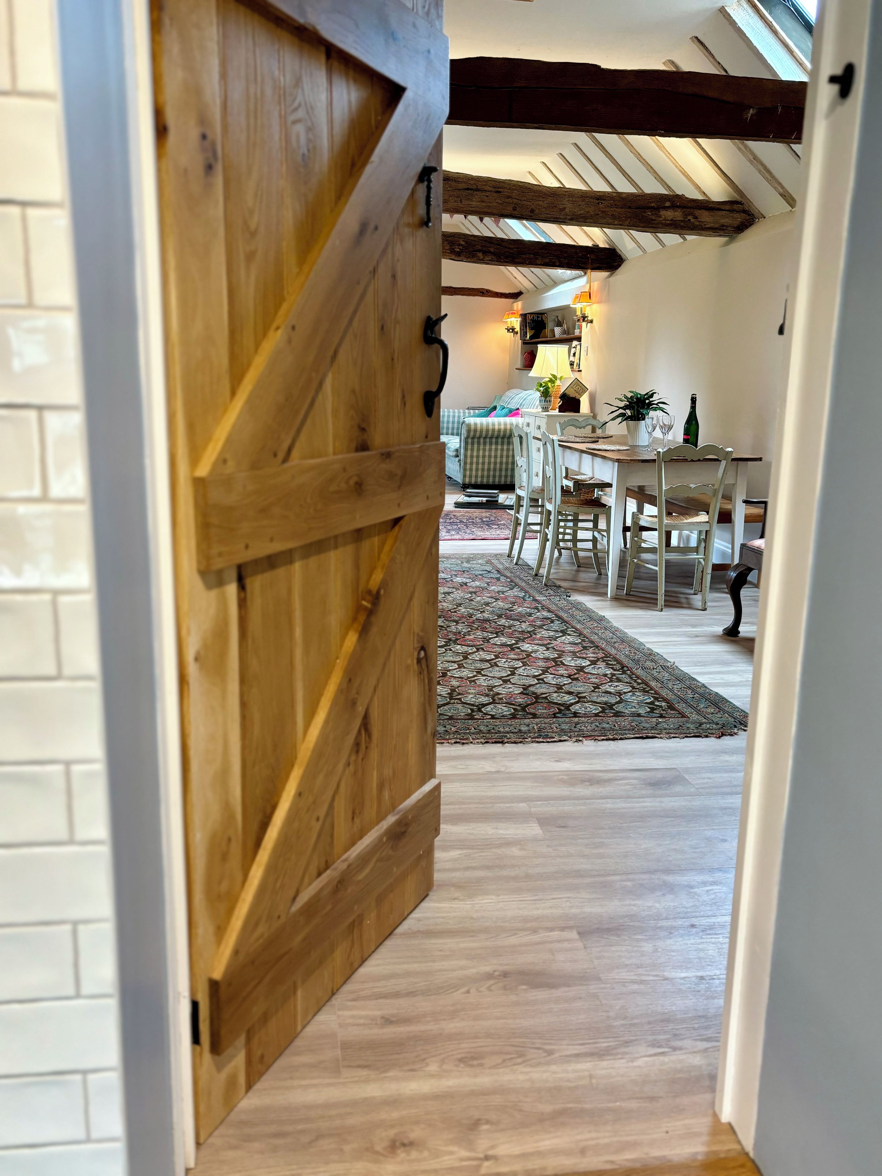A wooden barn-style door leading to a dining area with a table, chairs, and a rug.