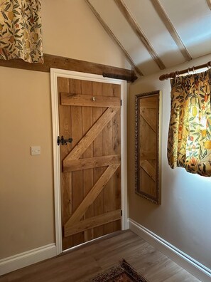A wooden door with a diagonal brace, a mirror on the wall, and a patterned curtain.