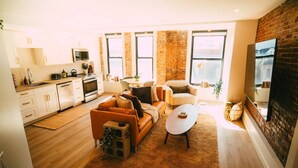 A modern living space with a kitchen, a sofa set, a coffee table, and a brick wall. - Free Parking Historic 1BR plus Den DT Halifax (Halifax)