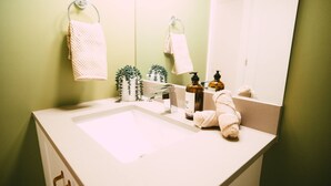 A bathroom with a white sink, a mirror, a towel, and a bottle of hand soap. - Free Parking Historic 1BR plus Den DT Halifax (Halifax)
