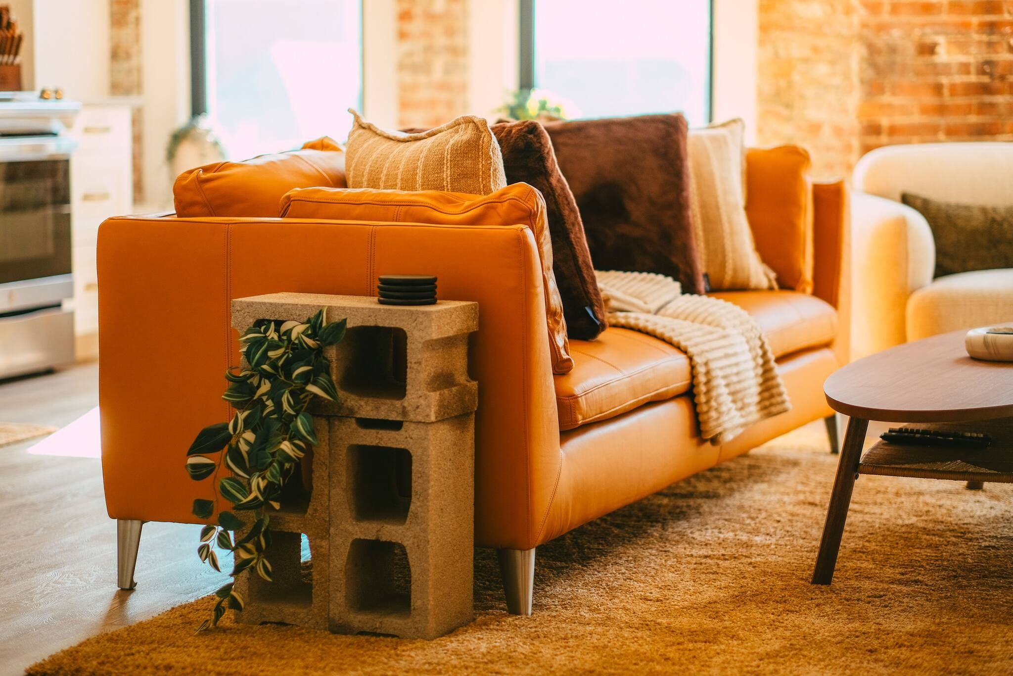 Ein modernes Wohnzimmer mit einer Ledersofa, einem Couchtisch und einem einzigartigen Dekoelement aus Betonsteinen mit einer Pflanze.