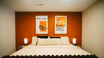 A hotel room with a large bed, two bedside lamps, and two framed posters on the wall.