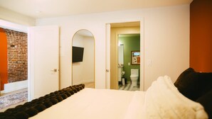 A hotel room with a bed, a television mounted on a wall, and a view of the bathroom. - Free Parking Historic 1BR plus Den DT Halifax (Halifax)